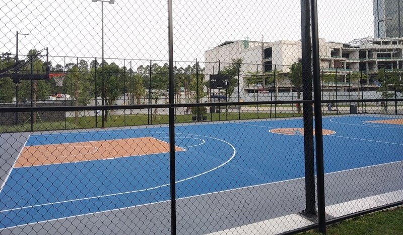 Lapangan basket luar ruangan dengan warna biru dan pagar kawat.