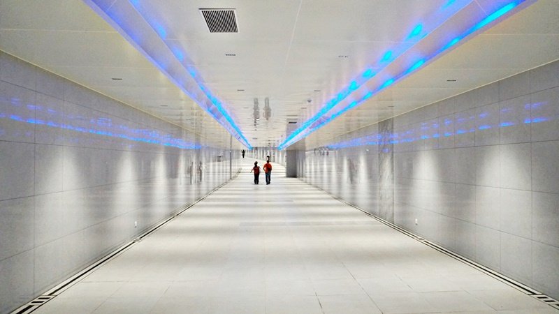 Terowongan bawah tanah dengan nuansa putih dan lampu pemandu.