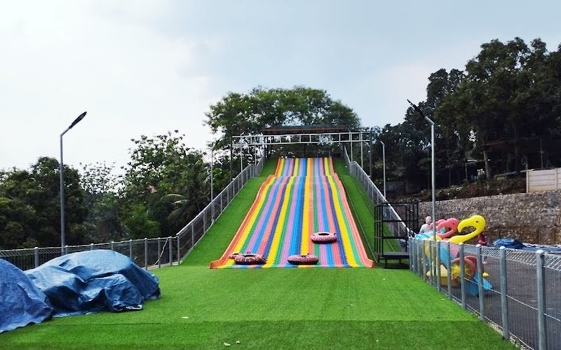 Seluncur pelangi di atas kontur bukit buatan.